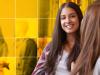 Young female student speaks to a friend while holding textbooks