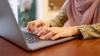An unseen person at a laptop typing