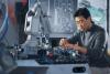 Male Asian student working on a robot arm