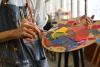 An artist mixes paints on a palette