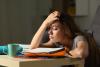 A student slumps over a pile of paperwork