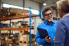 A businessman in a warehouse speaks to a business partner.