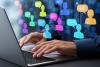 Man's hands over laptop keyboard with figures and speech bubbles