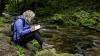 A student on a field trip in the forest taking notes 