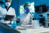 Two masked scientists fillin test tubes in a lab