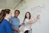 Secondary students solving a maths problem on a whiteboard
