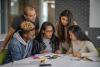 Students gather around a table to work together