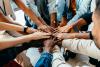 Team members place their hands in a circle