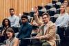Student raising their hand to speak in a lecture