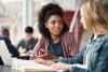 Two female college students discussing something in class