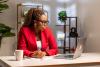 A Black female academic with glasses sat at a desk on her laptop